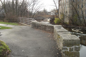 Cedar Creek Walkway - Path by Short Wall, Water, and Building in the Distance
